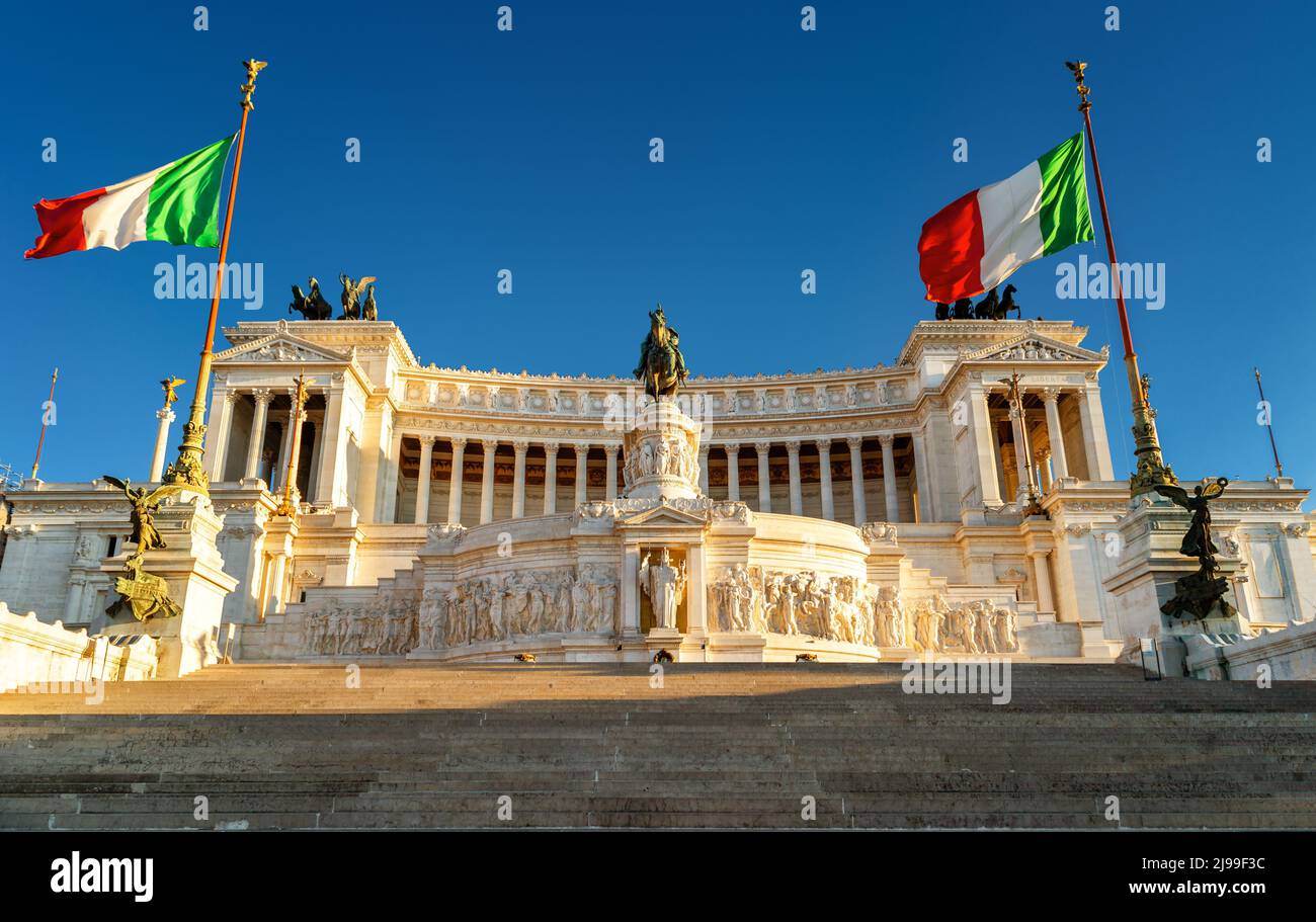 Palazzo Vittoriano con bandiere italiane in Piazza Venezia al tramonto, Roma, Italia. E' un punto di riferimento di Roma. Vista soleggiata dell'architettura classica al Campidoglio Foto Stock