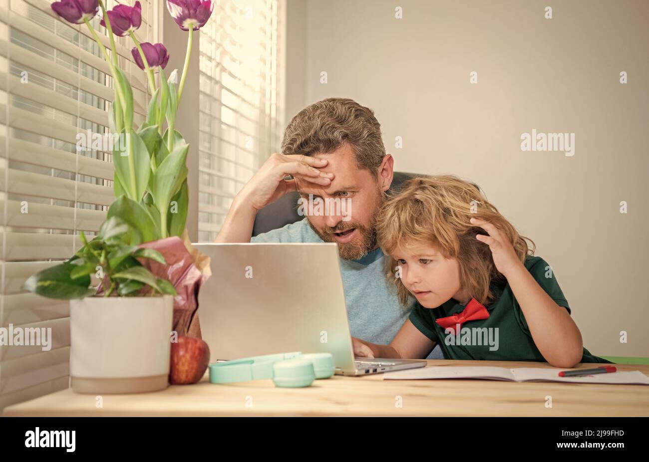 insegnante o papà uomo maturo che aiuta il figlio del bambino con i compiti a scuola sul computer, videoconferenza Foto Stock