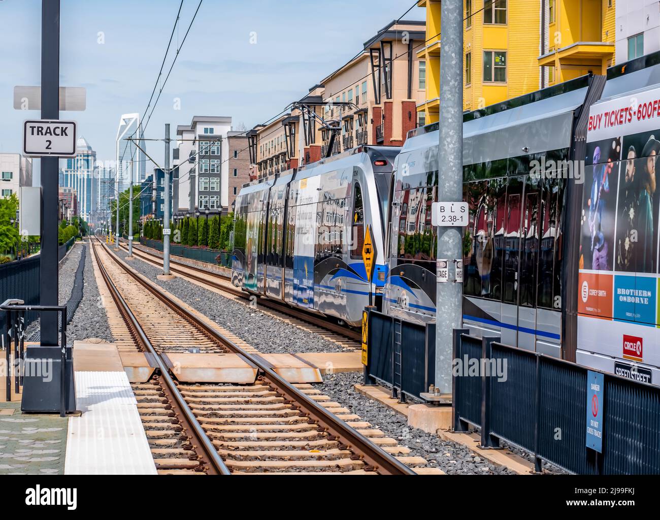 Treno per pendolari Lynx Blue Line che porta nella parte alta di Charlotte, North Carolina, con edifici alti, edifici di appartamenti e binari ferroviari. Foto Stock