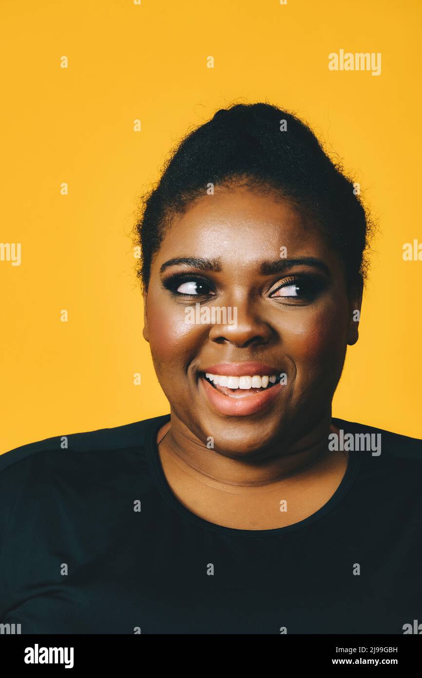 primo piano ritratto di una bella giovane donna afroamericana con acconciatura afro su sfondo giallo studio Foto Stock