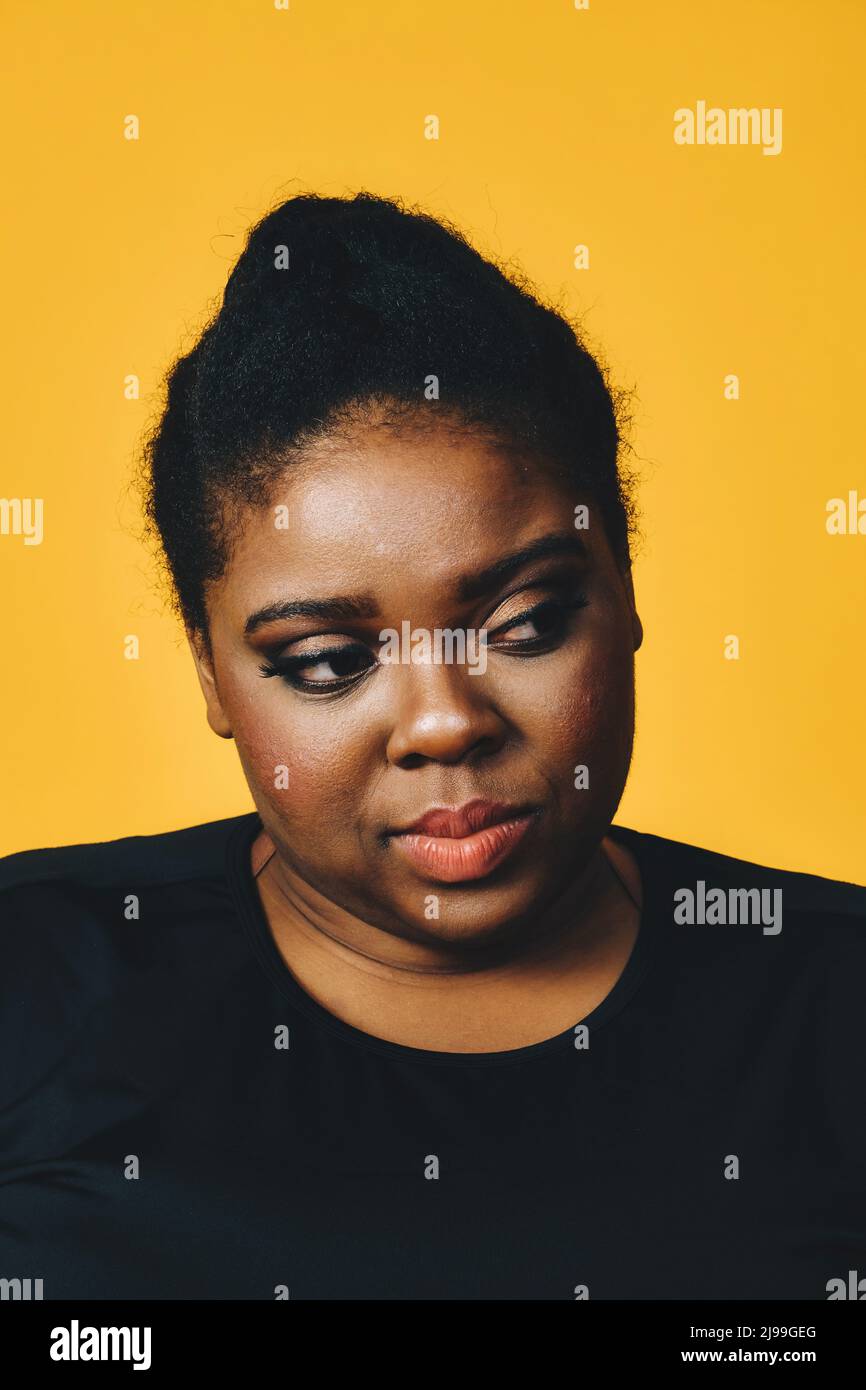 primo piano ritratto di una bella ragazza afroamericana giovane e premurosa con acconciatura afro su sfondo giallo studio Foto Stock