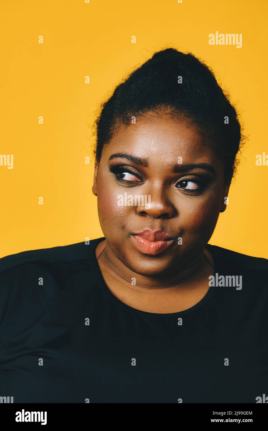 primo piano ritratto di una bella giovane donna afroamericana con acconciatura afro su sfondo giallo studio Foto Stock