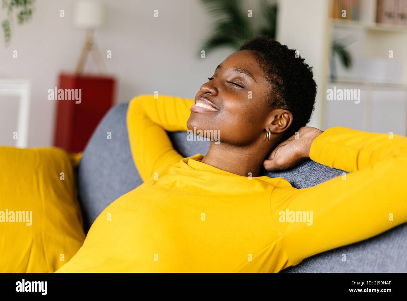 Giovane afroamericana che si rilassa sul divano di casa Foto Stock