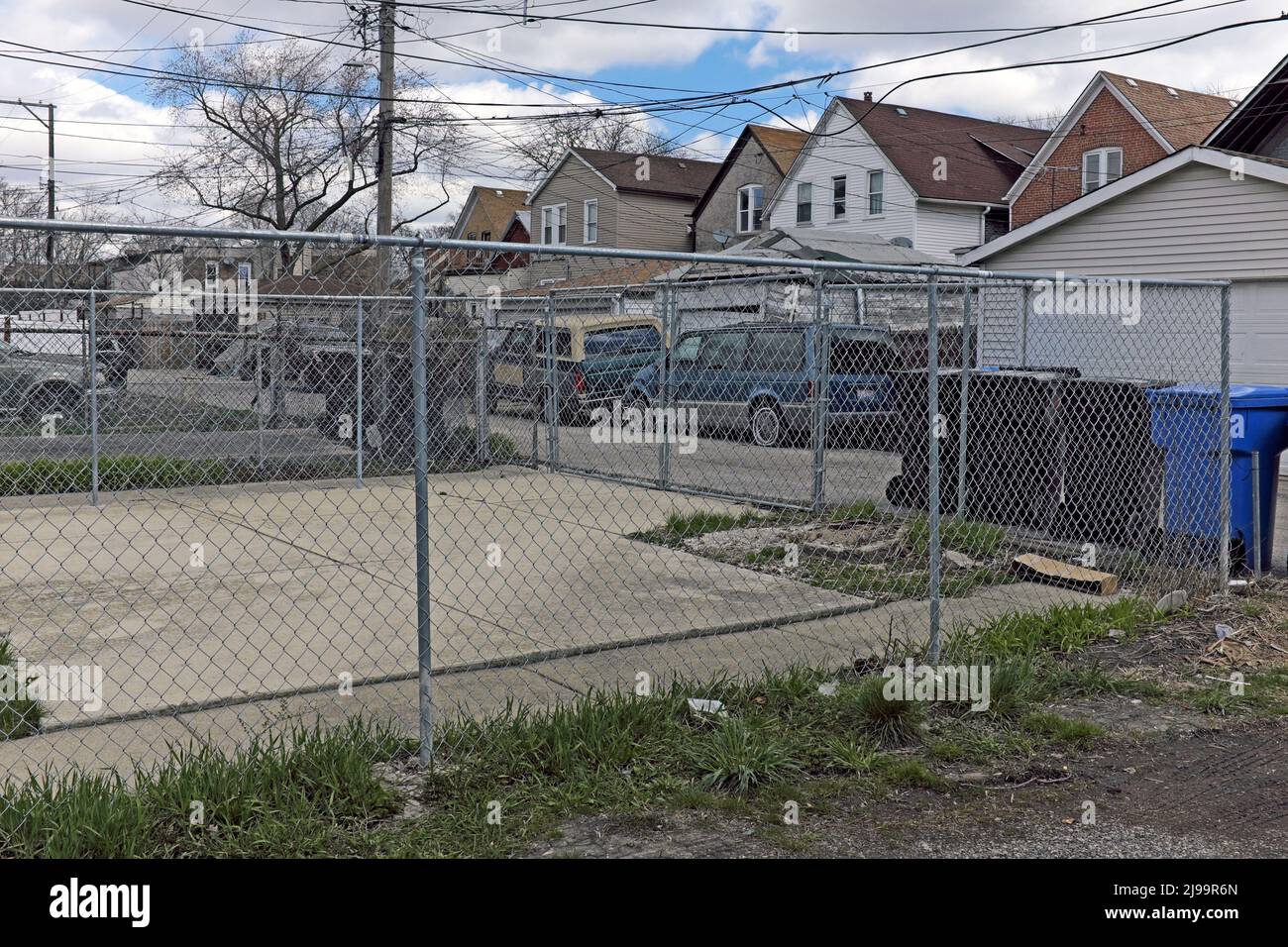 Le auto e bidoni della spazzatura fiaccano il vicolo dietro la casa di famiglia 'Gallagher' nel quartiere North Lawndale di Chicago, Illinois. Foto Stock