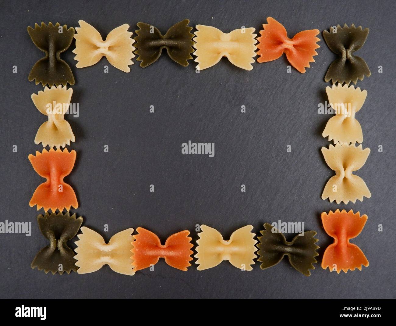 una cornice di noodle farfalla su sfondo nero.farfalle Foto Stock