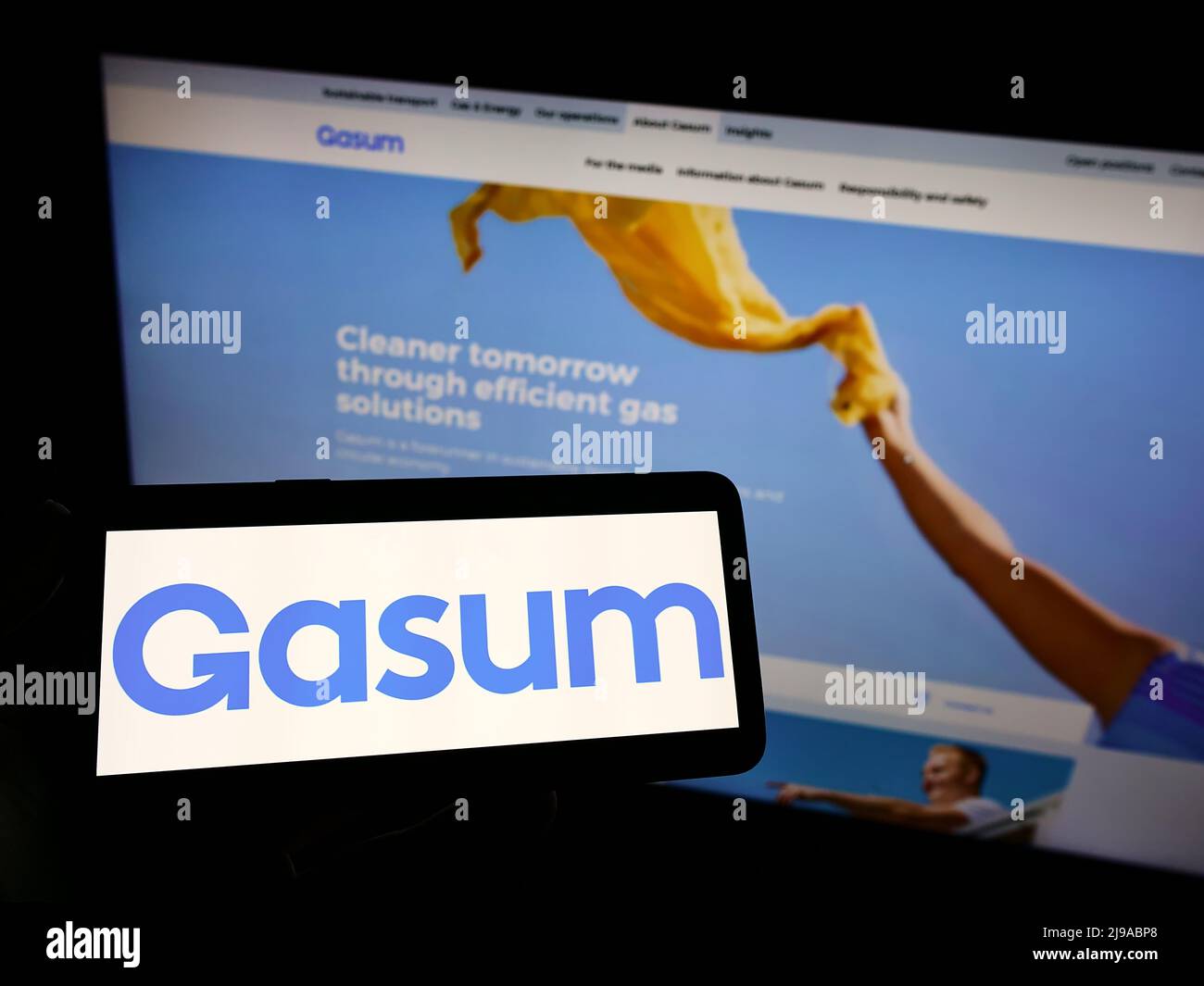 Persona che tiene uno smartphone con il logo della società finlandese di gas di proprietà statale Gasum Oy sullo schermo di fronte al sito web. Mettere a fuoco sul display del telefono. Foto Stock