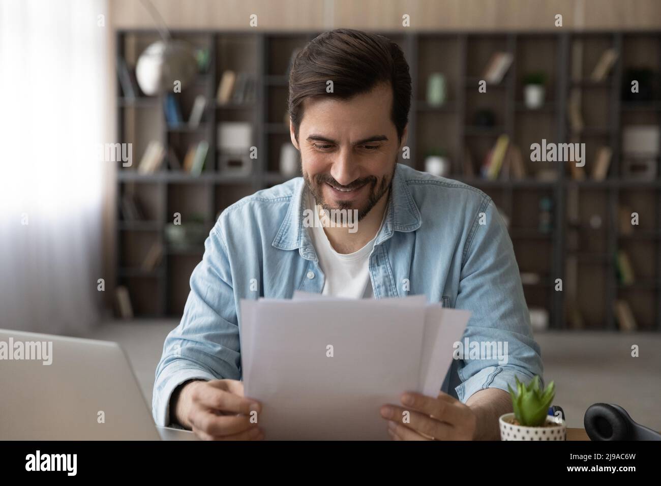 Sorridendo giovane dipendente a distanza maschio ricevere lettera di accreditamento cartaceo Foto Stock