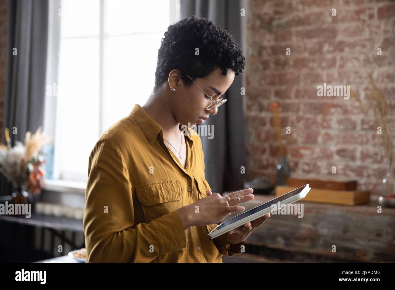 Donna africana seria e focalizzata che lavora con tablet digitale Foto Stock