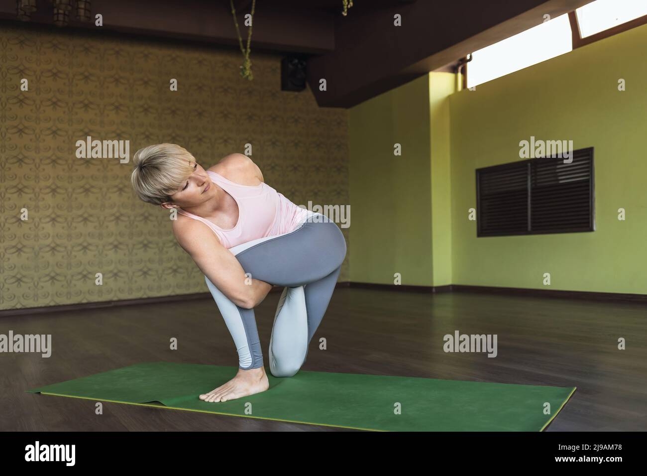 Donna che fa vatajanasana esercizio, cavallo posa, esercizio su tappeto in studio Foto Stock