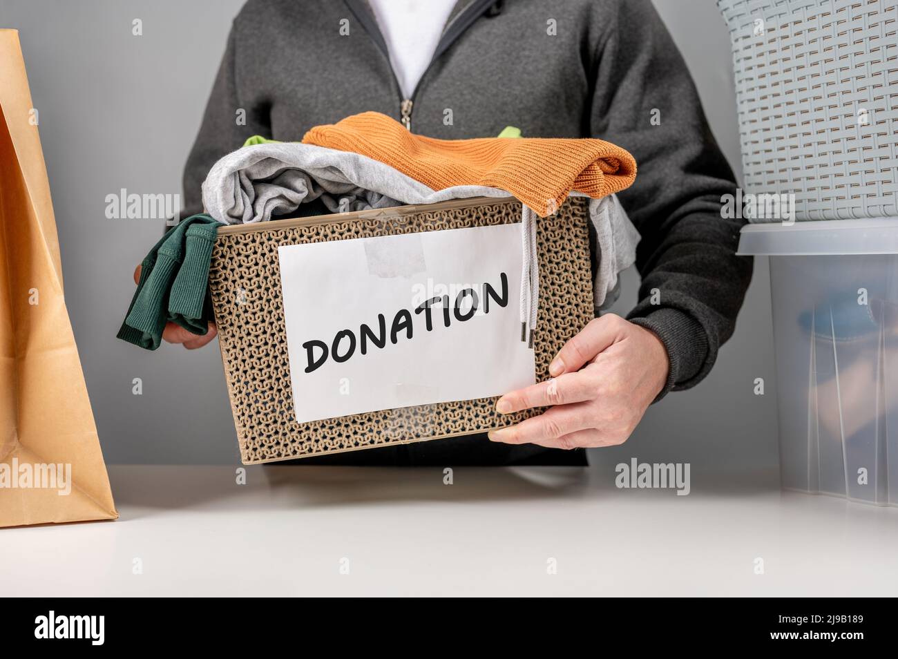 Concetto di donazione. Scatola di donazione con abiti da donazione. Aiutare persone povere e bisognose. Box per poveri con abbigliamento in mani maschili. Beneficenza e donazione co Foto Stock