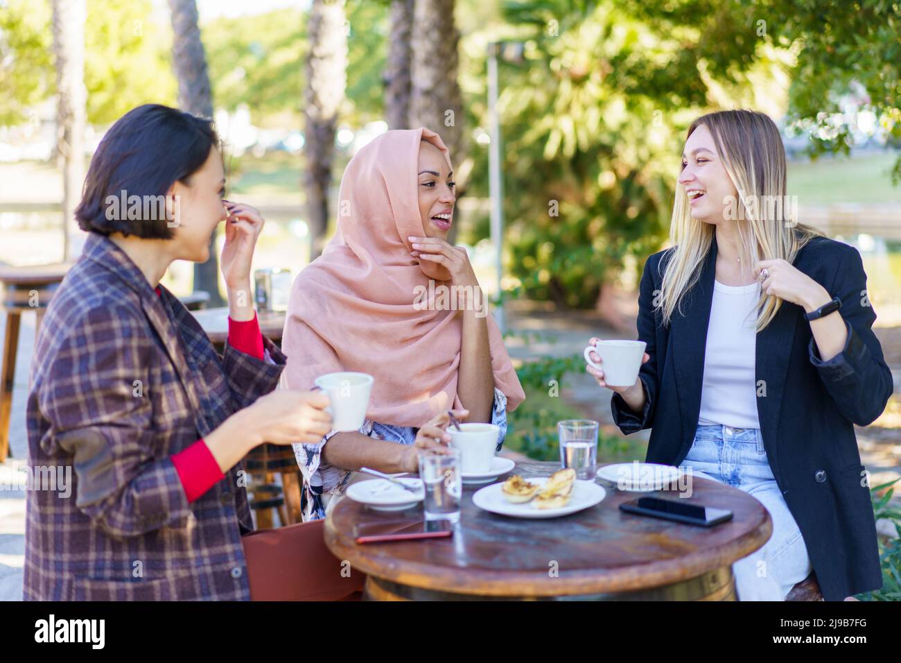 Gioiose donne multirazziali che chiacchierano sulla terrazza del caffè Foto Stock