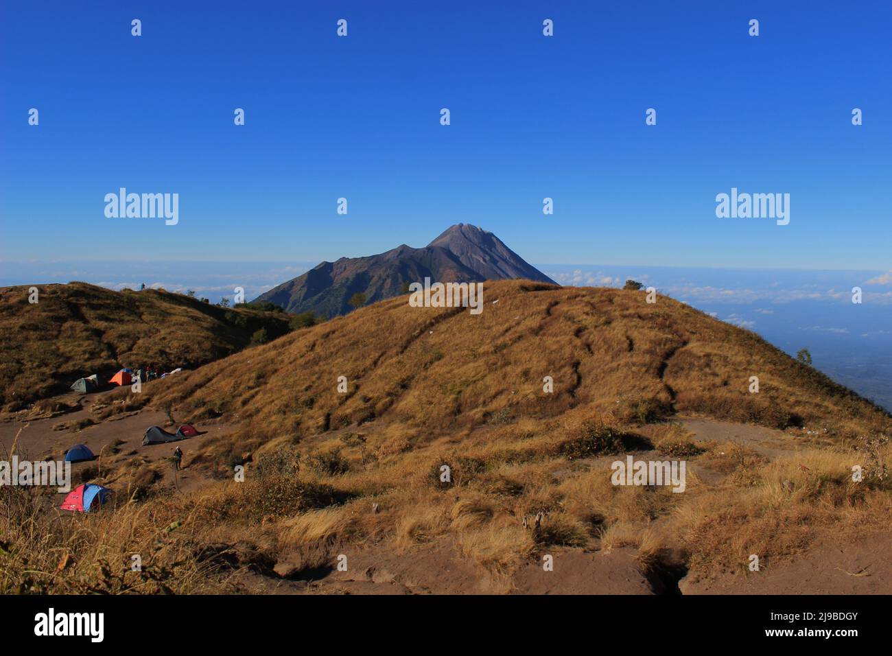 Vista dell'erba marrone e del cielo che si estende sulla cima del Monte Merbabu Foto Stock