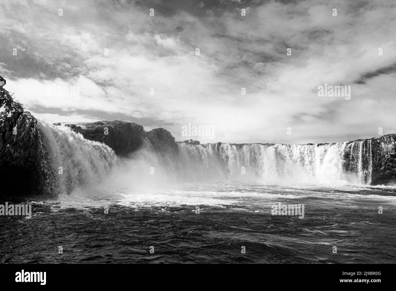 Goðafoss, la « Cascata degli Dei » sul fiume Skjálfandafljót a Bárðardalur, nel nord dell'Islanda, scompare in una fitta nebulosa con una delle sue cascate. Secondo la leggenda islandese, il portavoce delle leggi Þorgeir Ljósvetningagoði, capo di Ljósavatn, che viveva nella fattoria omonima, gettò le sue statue degli dei pagani nelle cascate nell'anno 1000, dopo la conversione del paese al cristianesimo, dando così il nome alla cascata. Goðafoss è larga circa 30 metri e alta da 9 a 17 metri, una delle cascate più ricche d'acqua del paese e un monumento naturale protetto dal 2020. Foto Stock