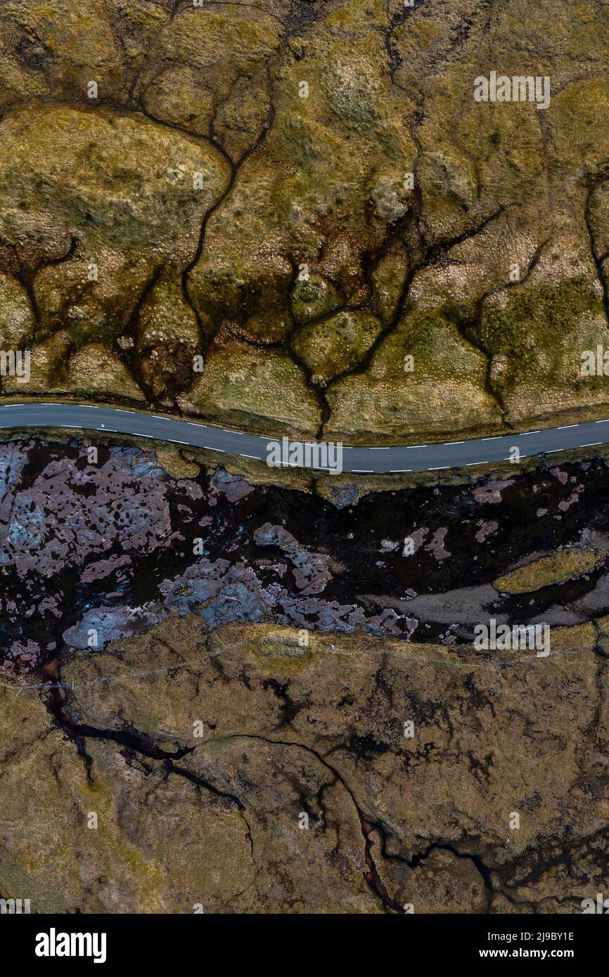Una vista aerea mostra una strada che passa attraverso splendidi paesaggi testurizzati sulle Isole Faroe. Foto Stock