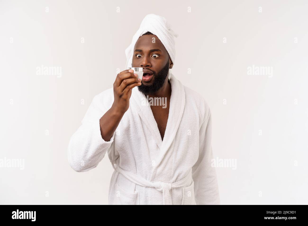 Sorridente uomo afroamericano che applica la crema sul suo viso. Il concetto di cura della pelle dell'uomo Foto Stock