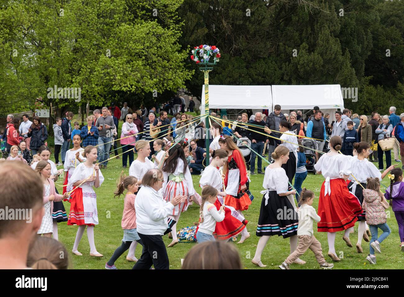 I bambini ballano intorno al Maypole sul verde del villaggio alla fiera di maggio dei Priori di Hurstbourne il 2nd 2022 maggio, Hampshire, Inghilterra Foto Stock