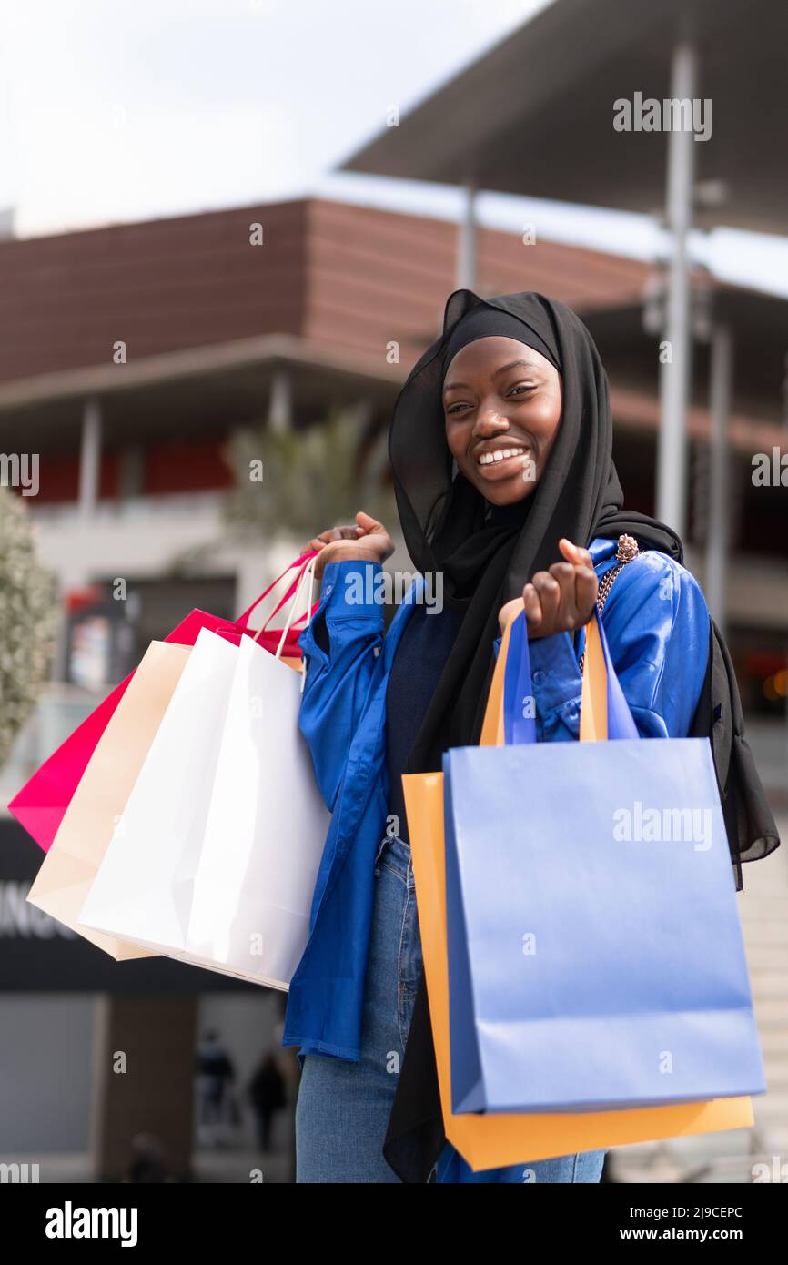 Allegro shopaholic musulmano con sacchetti di carta colorati Foto Stock