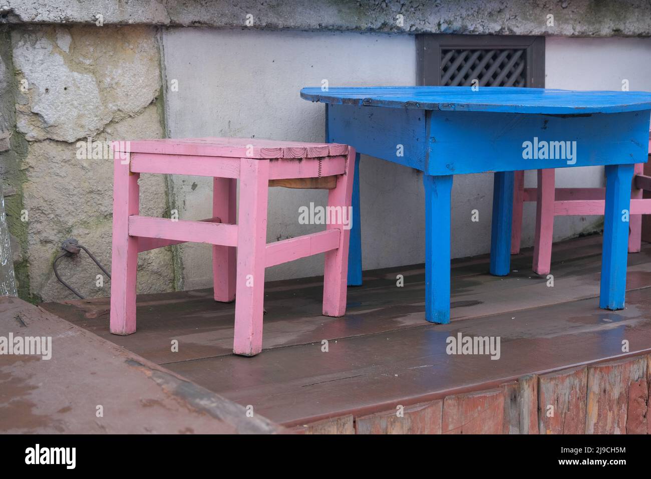 Caffè carino, piccole sedie rosa e tavolo giallo su terreno di legno in un grazioso caffè. Foto Stock