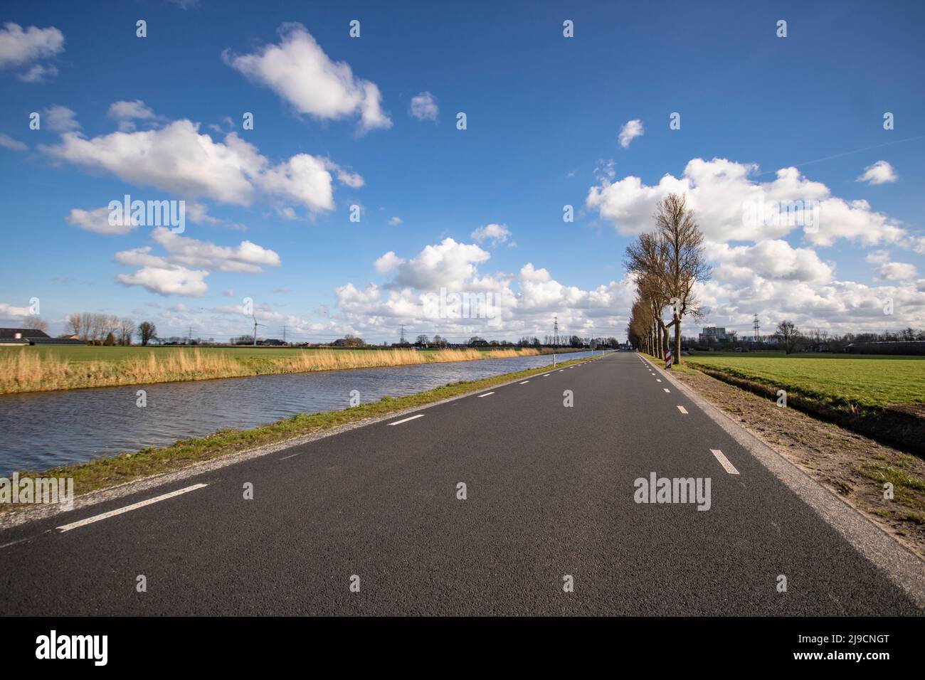 Strada diritta vicino al canale d'acqua in campagna pianeggiante Foto Stock
