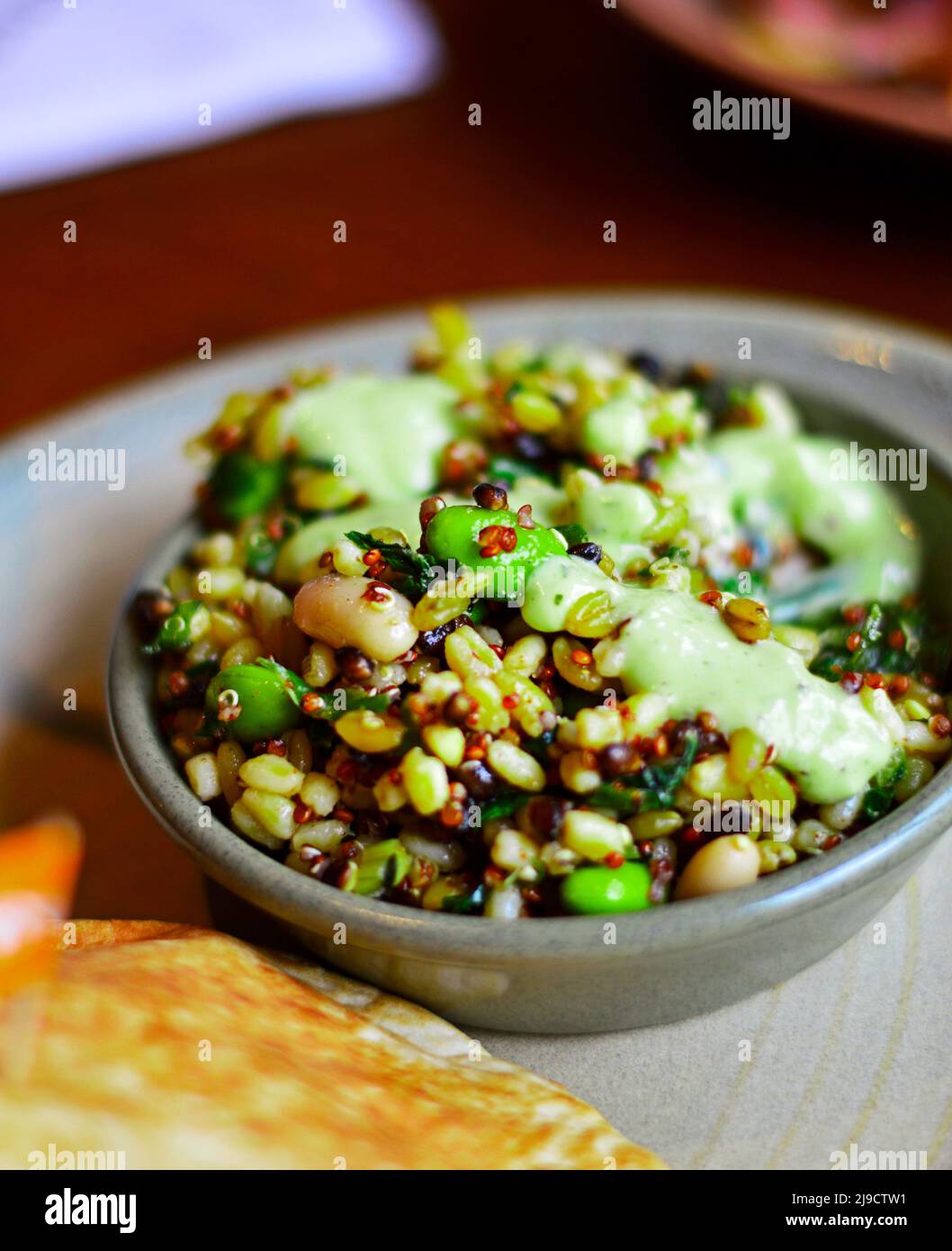 Insalata di superfood sana con proteine ricche tra cui quinoa, avocado, fagioli e cereali. Pane sfocato in primo piano Foto Stock