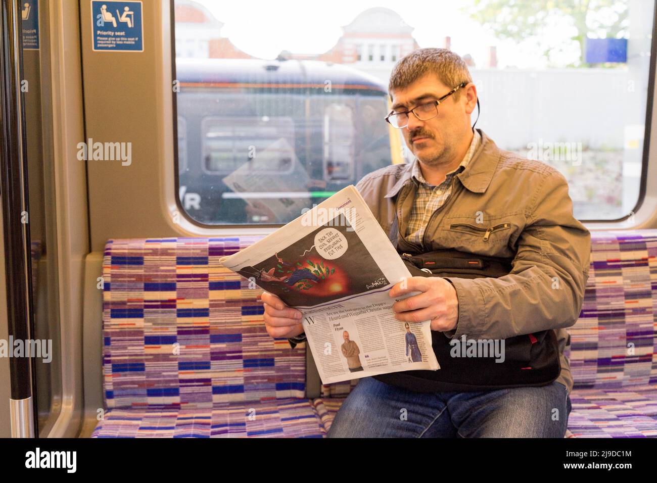 treno passeggeri lettura di un giornale su Elizabeth line , Crossrail, linea viola, Inghilterra Regno Unito Foto Stock