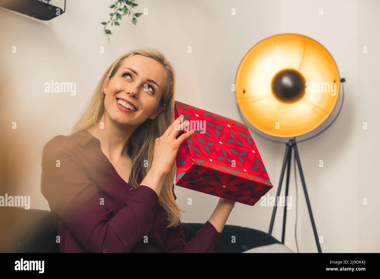 Attraente giovane donna che agita rosso borsa regalo floreale, guardando via concettuale copia spazio medio scatto. Foto di alta qualità Foto Stock