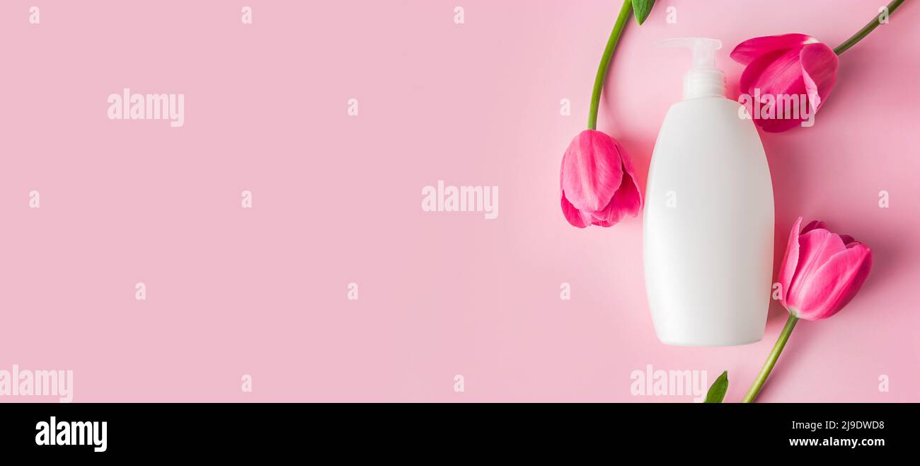 Spa prodotti per la cura della pelle su sfondo rosa. Cosmetici naturali e tulipani rossi. Formato intestazione, spazio di copia. Foto Stock