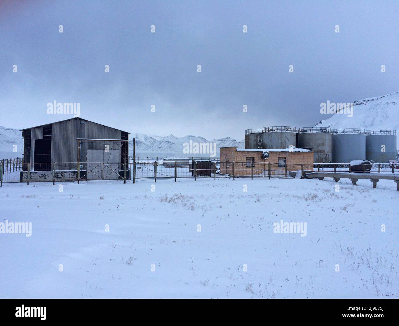 Edifici agricoli abbandonati presso l'ex insediamento minerario sovietico di Pyramiden a Svalbard. Pyramiden fu chiusa nel 1998 e fu in gran parte abbandonata. I minatori provenivano principalmente dalla regione di Donbas, nell'Ucraina orientale. Foto Stock