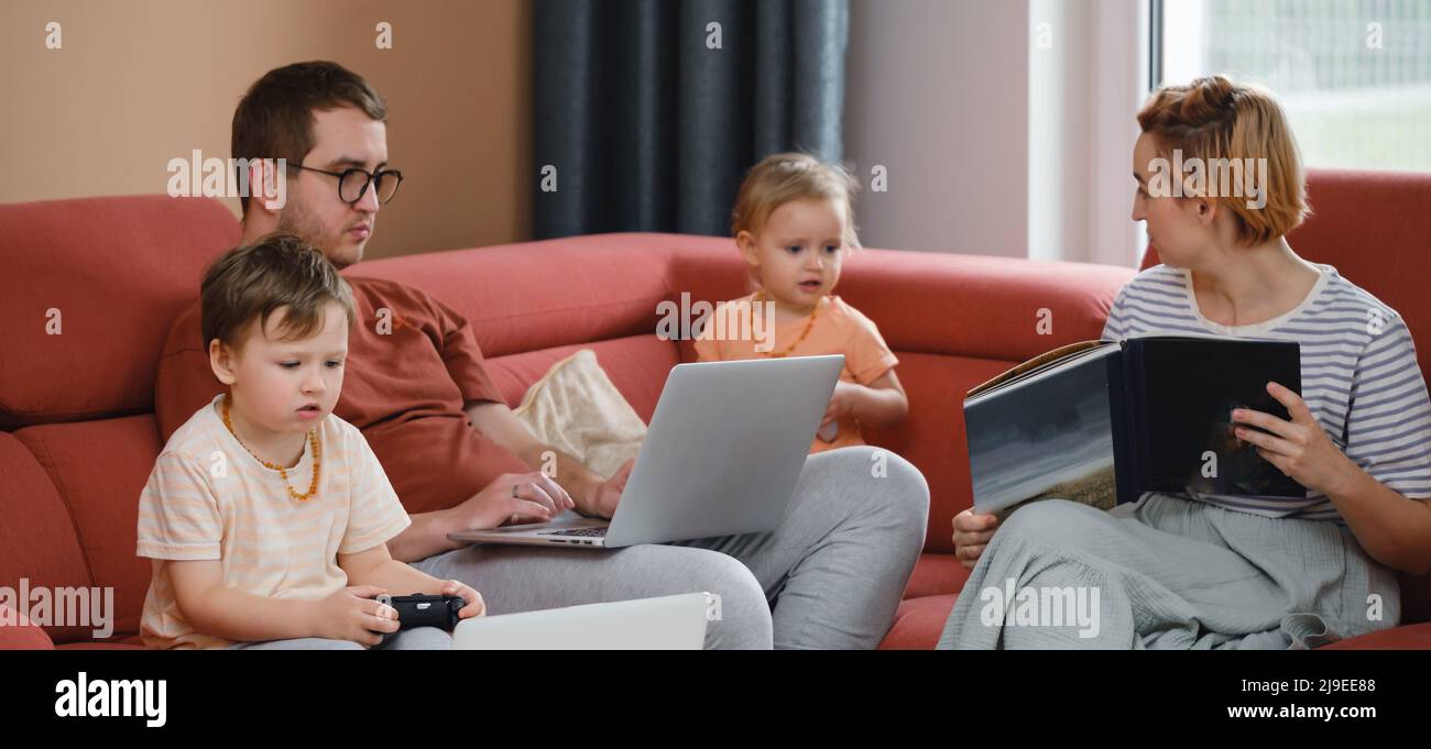 Grande famiglia felice di guardare film giocando a giochi su laptop. Madre padre bambini passare il tempo con gadget sul divano bambini con i genitori che cercano Foto Stock