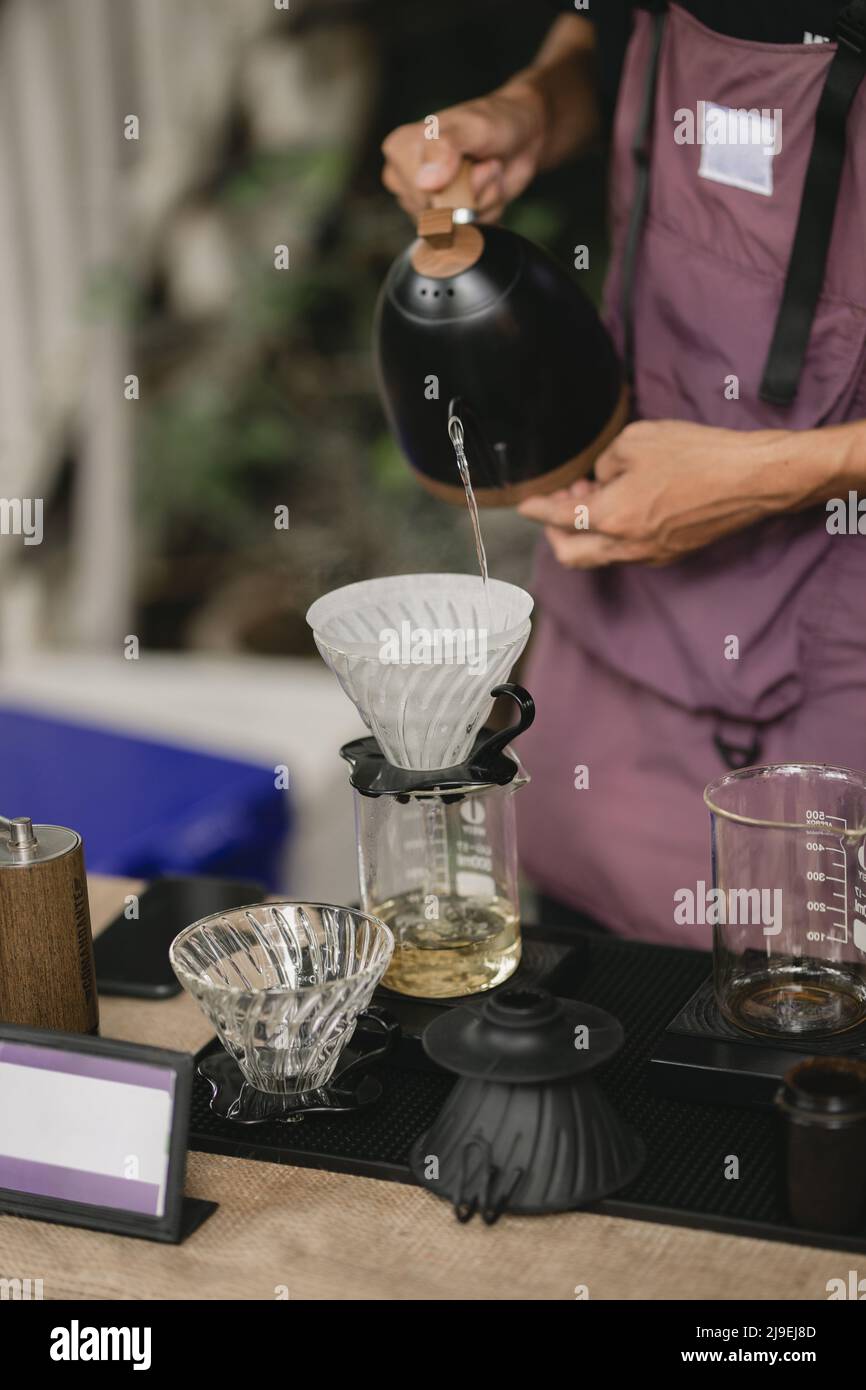 Il barista professionale prepara il caffè utilizzando la macchina per caffè chemex pour Over e il bollitore antigoccia Foto Stock