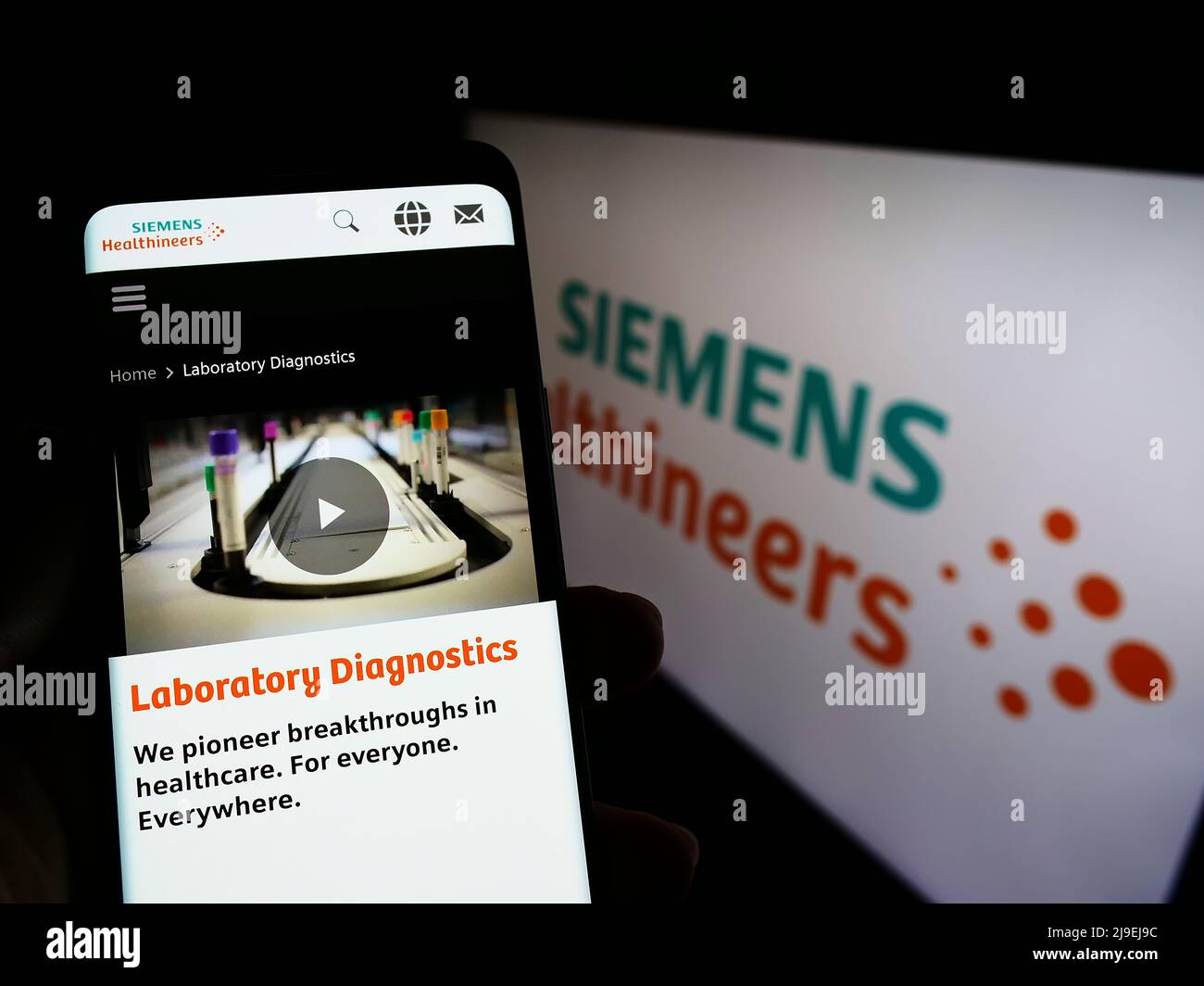 Persona che tiene il cellulare con il sito web della società tedesca Siemens Healthineers AG sullo schermo di fronte al logo. Concentrarsi sul centro del display del telefono. Foto Stock