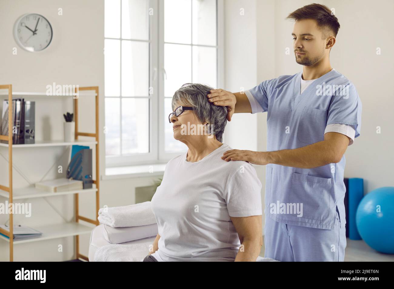 Il fisioterapista aiuta il paziente maturo con sollievo dal dolore Foto Stock