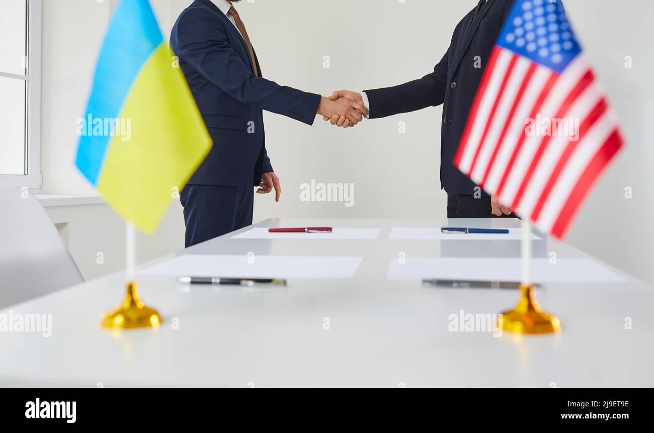 I politici di sesso maschile provenienti da America e Ucraina scuotono le mani dopo aver accettato di firmare il contratto di locazione per l’Ucraina. Foto Stock