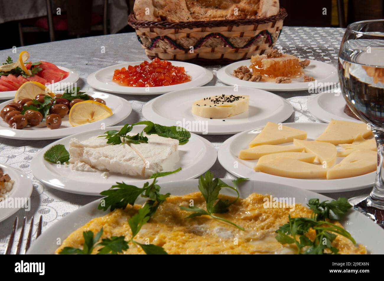 Un tavolo per la colazione con una varietà di cibi. Ci sono alimenti come uova, burro, miele, marmellata, tè, pane, formaggio, pomodori, omelette sul tavolo. Foto Stock