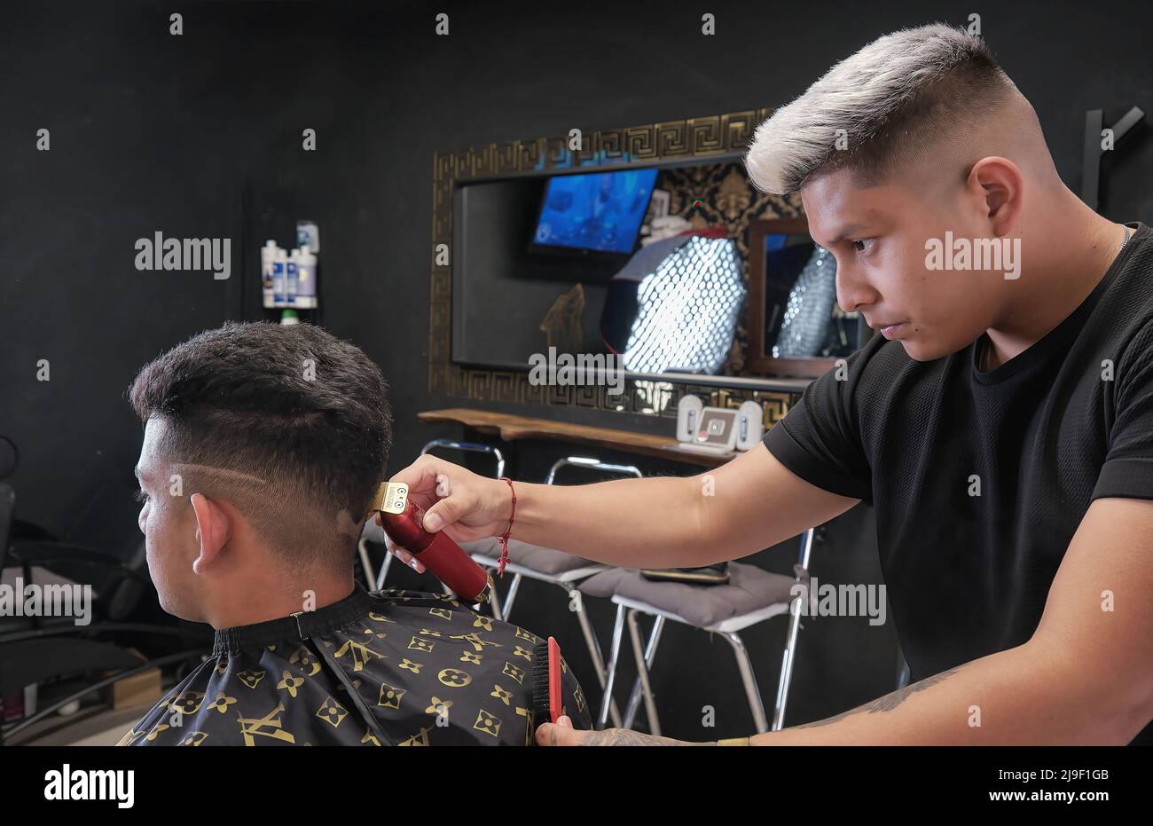 Giovane uomo in barbiere taglio capelli in nero vintage business Foto Stock