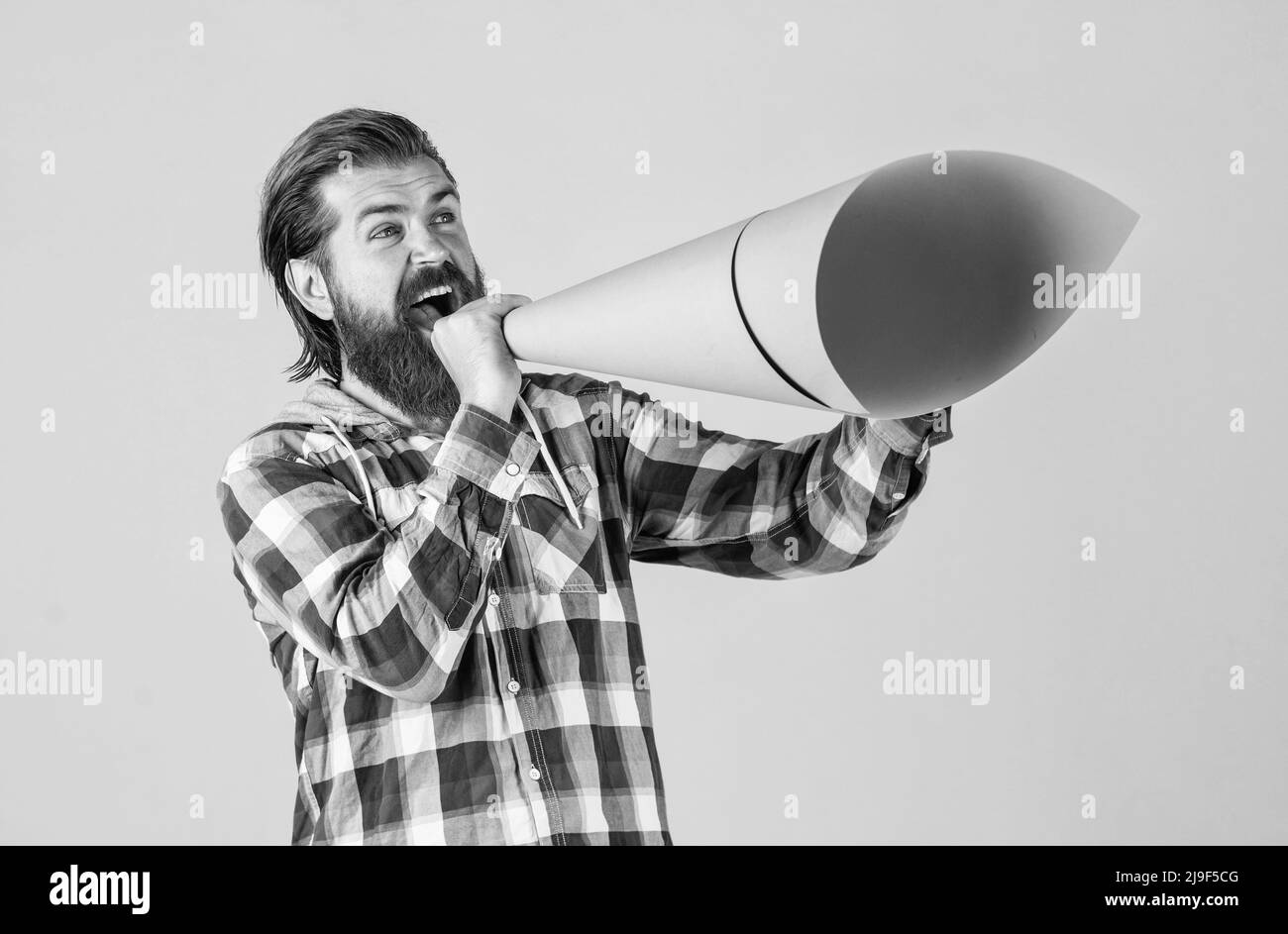 l'uomo maturo bello in maglia a scacchi parla in altoparlante di carta, annuncio Foto Stock