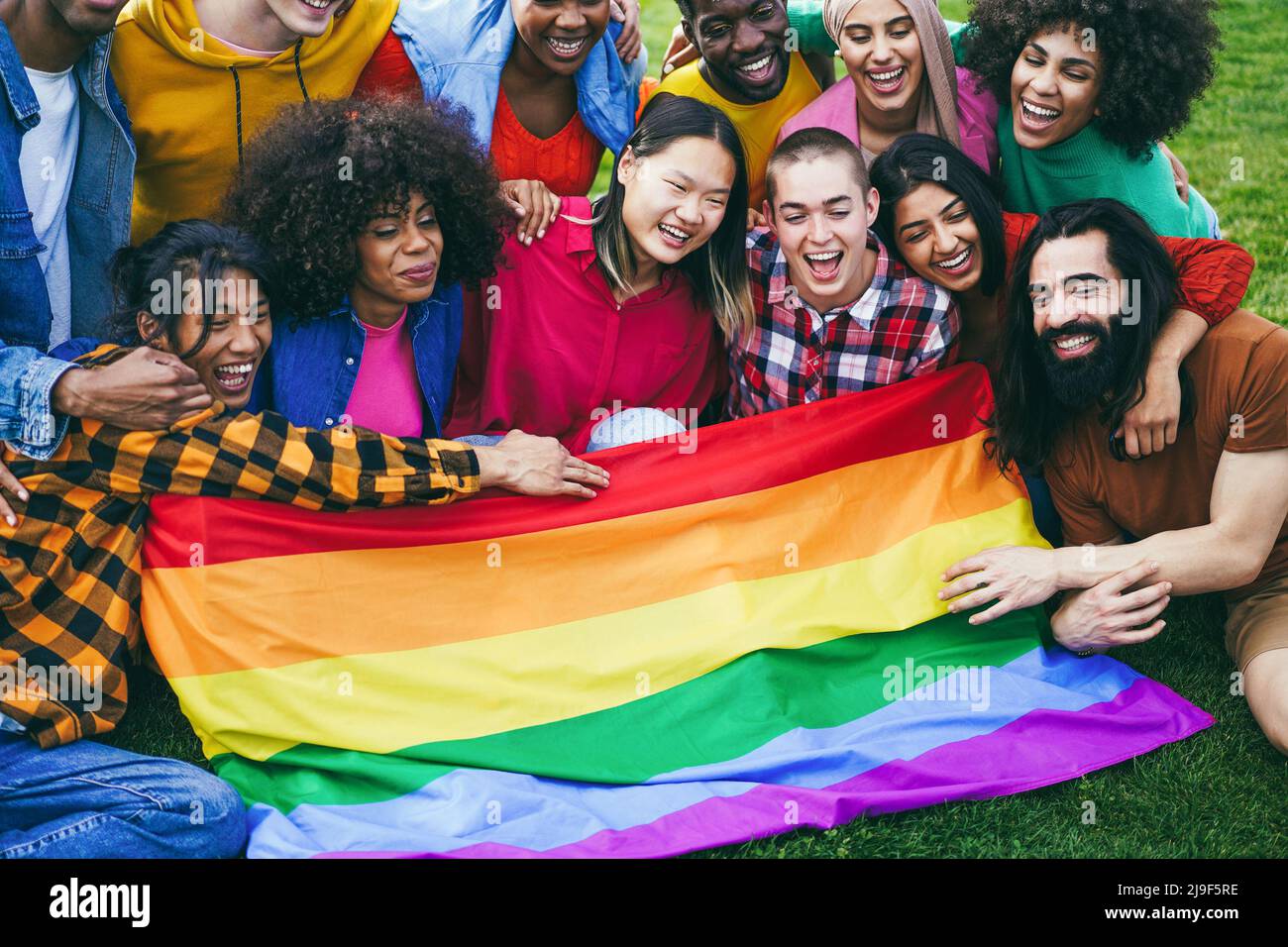 Persone diverse che hanno divertimento tenendo la bandiera arcobaleno LGBT all'aperto - Focus sul volto della ragazza calva Foto Stock