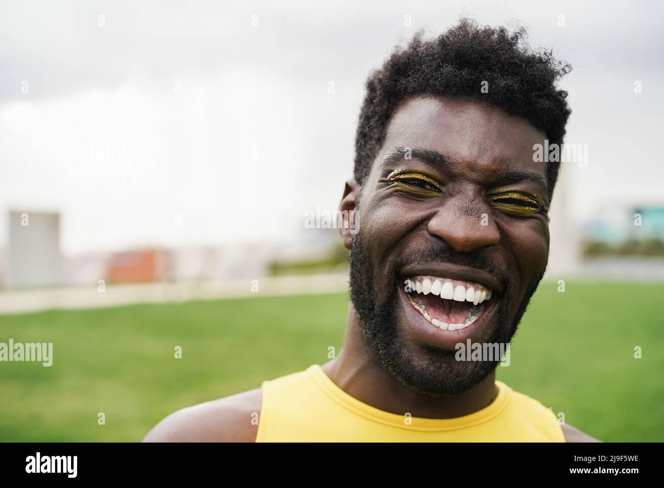 Happy gay african man con make-up sorridente a macchina fotografica al parco della città - Focus on Face Foto Stock