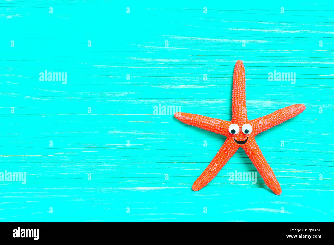 Carattere di stelle rosse con occhi d'oca su uno sfondo di legno turchese con spazio copia. Foto Stock