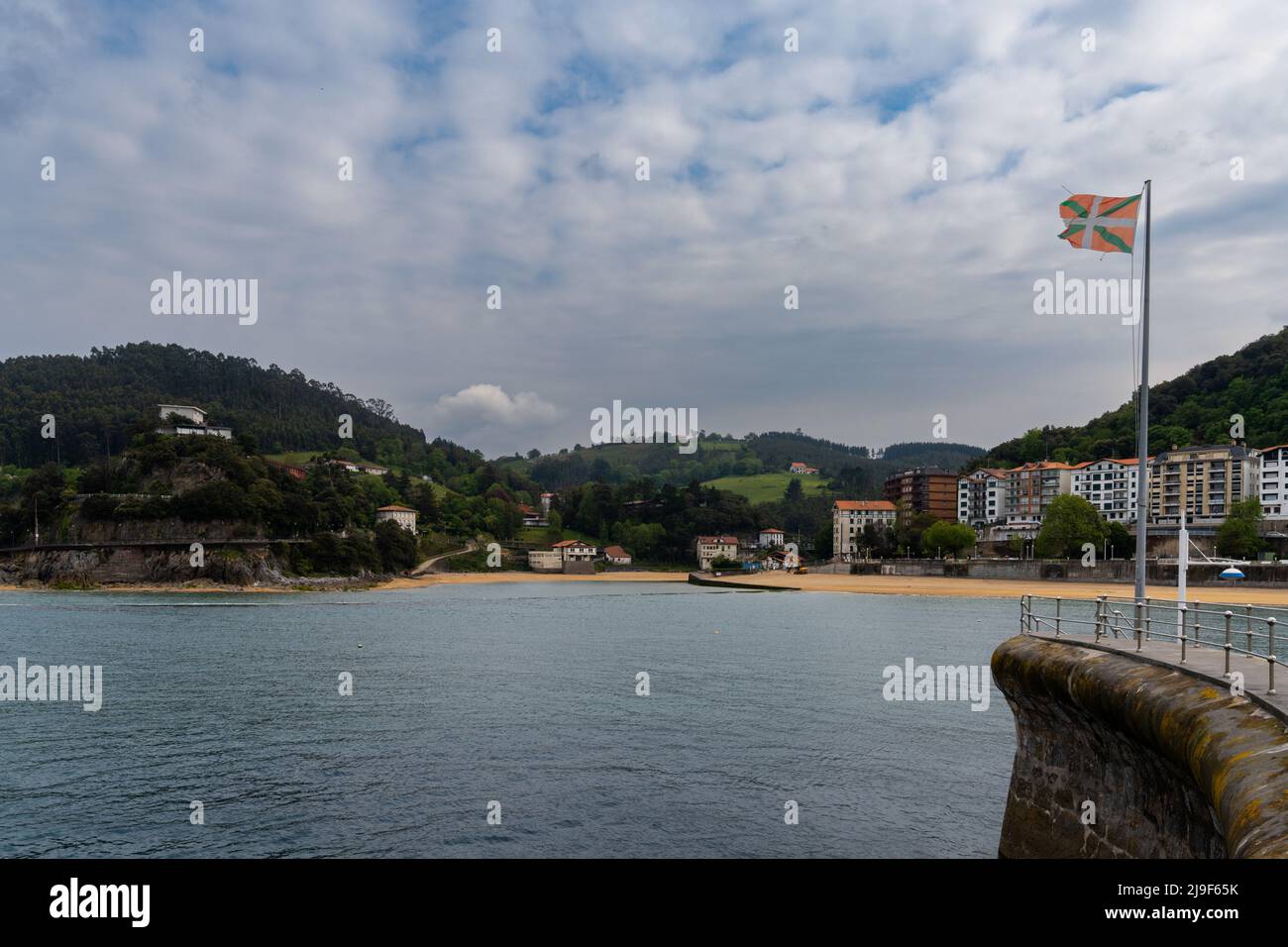 Lekeitio, Spagna - 4 maggio 2022: Vista sulla spiaggia e sul porto di Lekeitio con una bandiera dei Paesi Baschi al vento Foto Stock