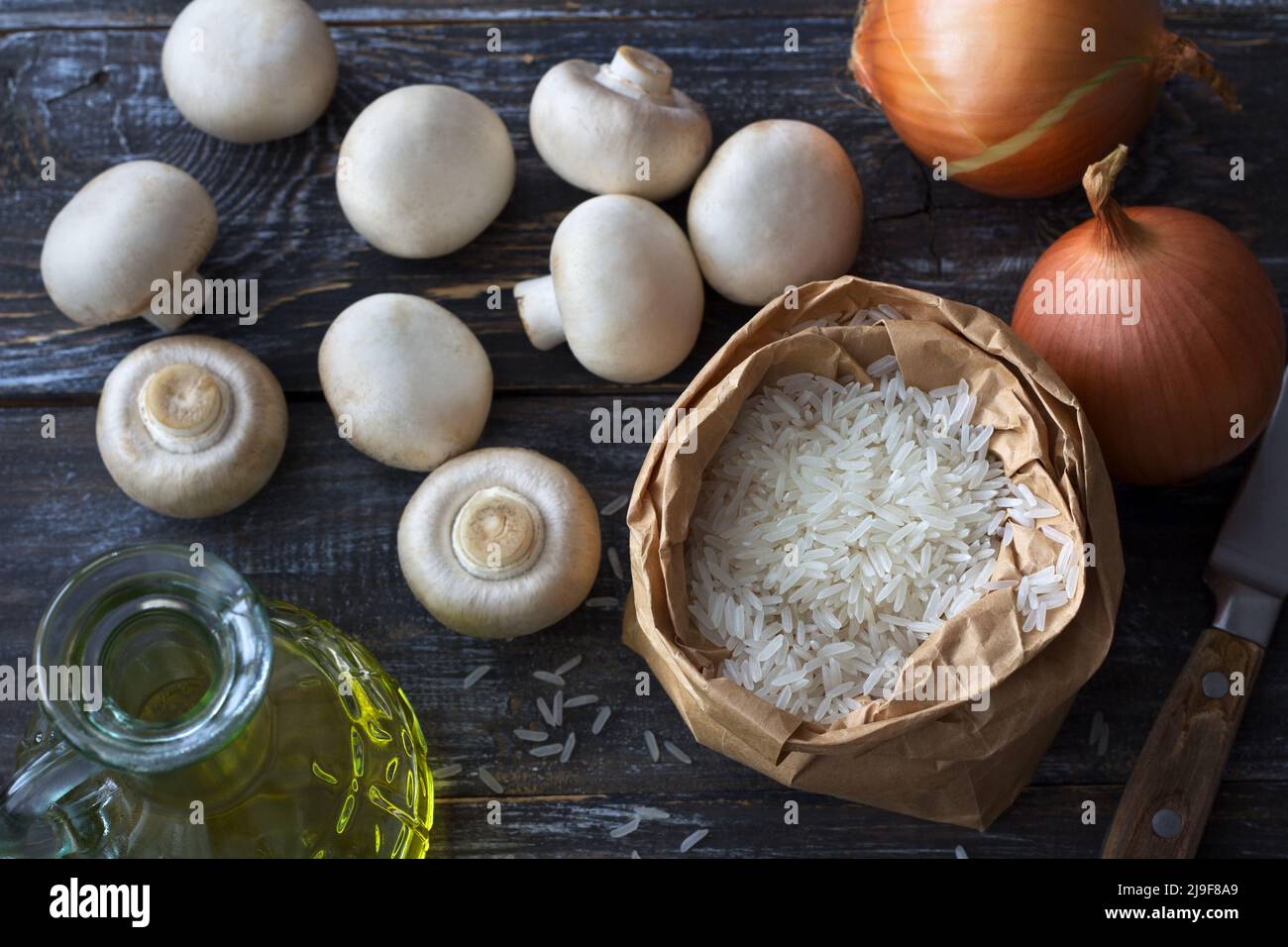 Ingredienti per un delizioso piatto vegano. Riso basmati bianco, aglio e champignons su un tavolo di legno, vista dall'alto, orizzontale Foto Stock