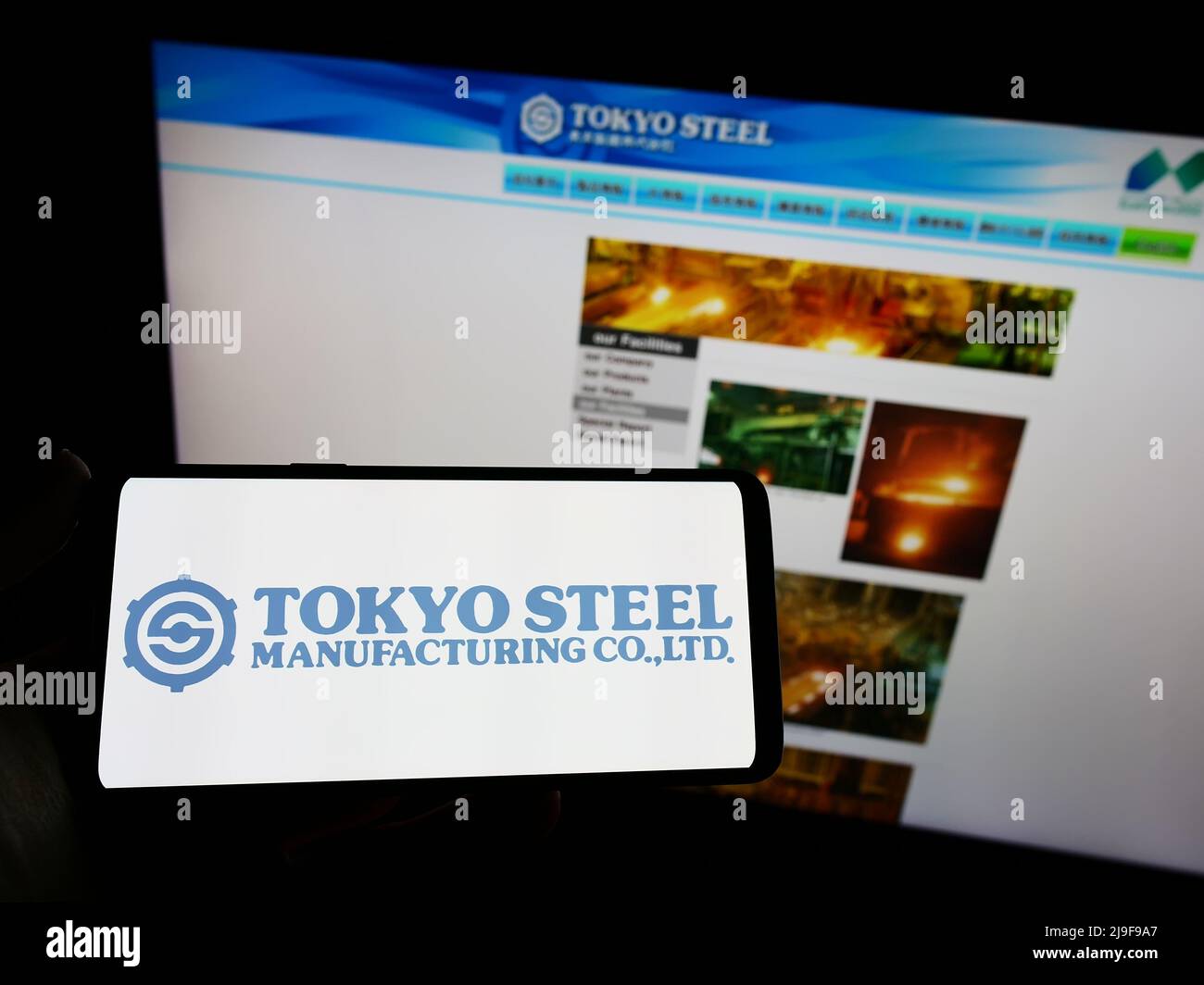 Persona che tiene smartphone con logo della società giapponese Tokyo Steel Co. Ltd sullo schermo di fronte al sito web. Mettere a fuoco sul display del telefono. Foto Stock