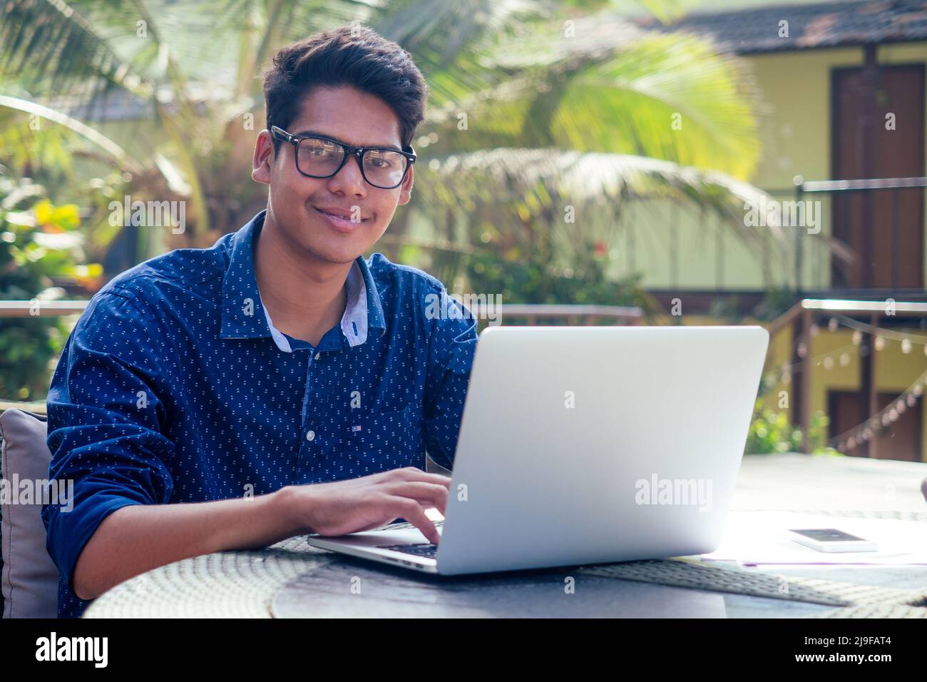bello e giovane uomo indiano di successo freelancing surf lavoro remoto con un laptop sulla spiaggia da parte del ocean.india uomo d'affari freelance Foto Stock