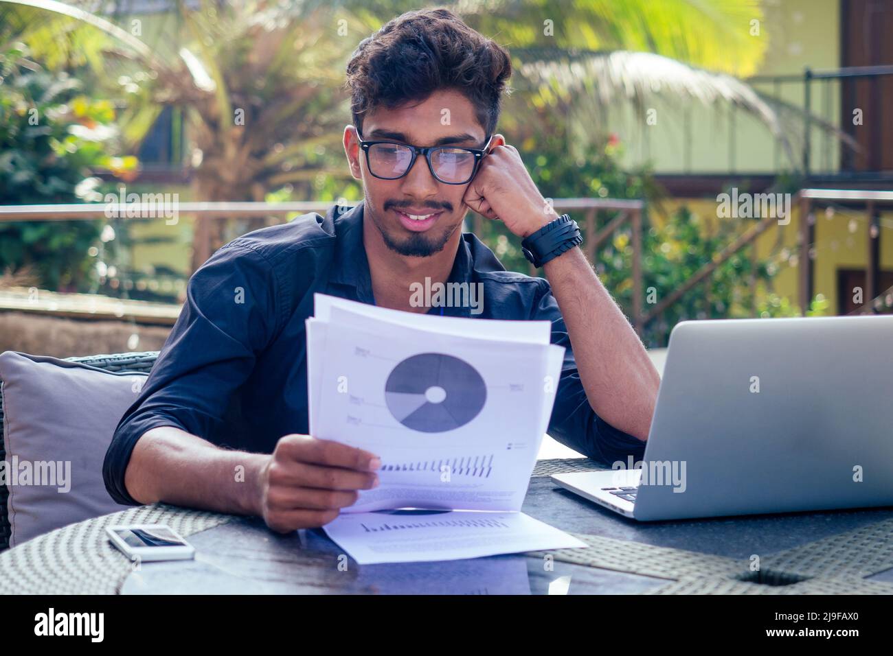 bello e giovane uomo indiano di successo freelancing surf lavoro remoto con un laptop sulla spiaggia da parte del ocean.india uomo d'affari freelance Foto Stock