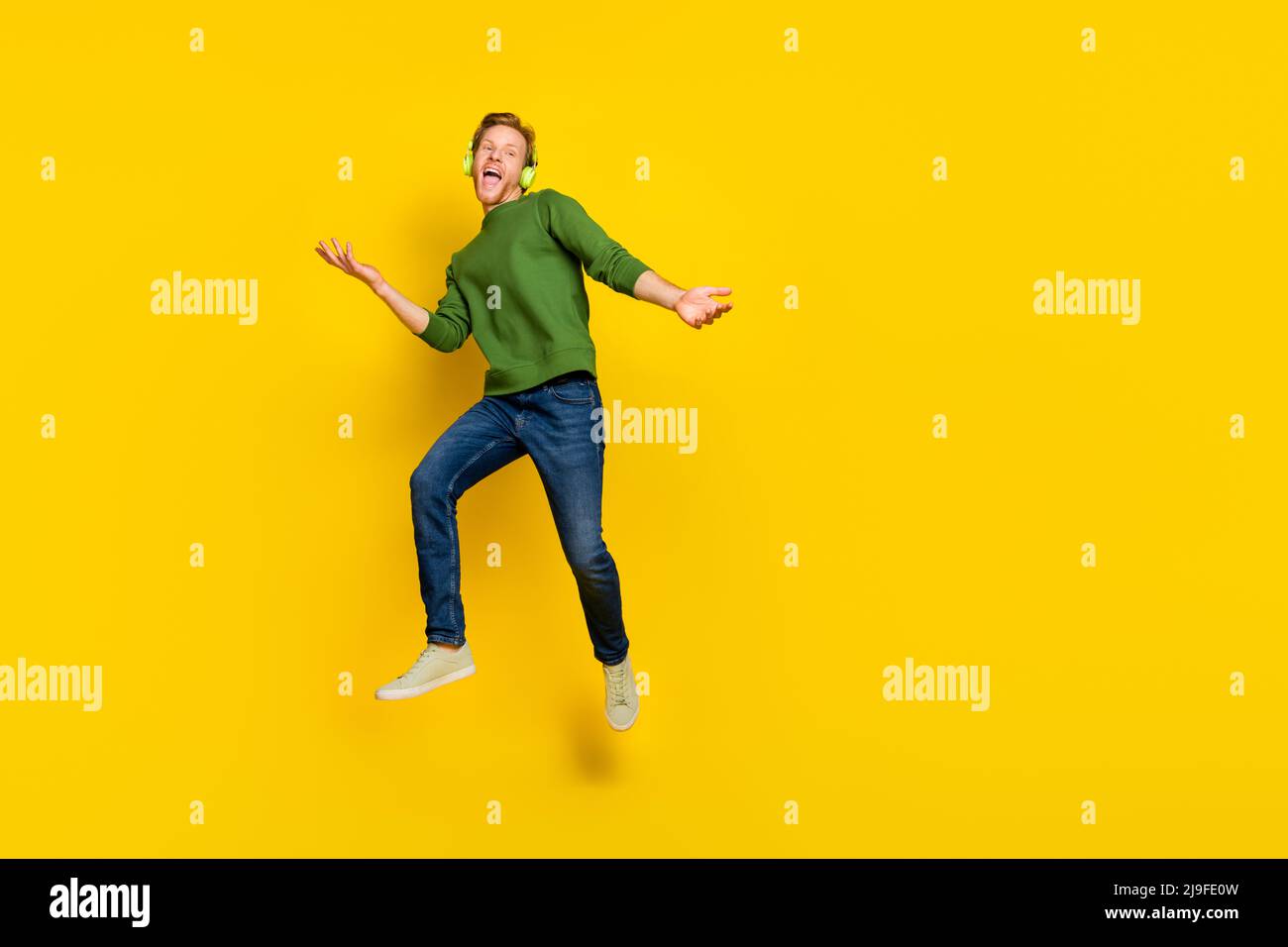 Foto a tutta lunghezza di funky grazioso uomo indossare cuffie pullover ascolto canzoni spazio vuoto isolato colore giallo sfondo Foto Stock
