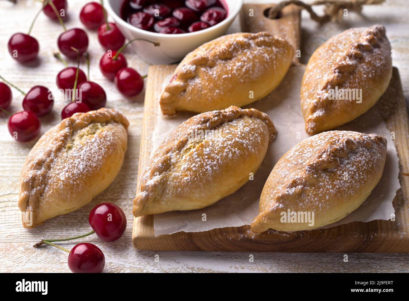 Dolci mini torte fatte in casa con ciliegia e cannella su sfondo di legno Foto Stock