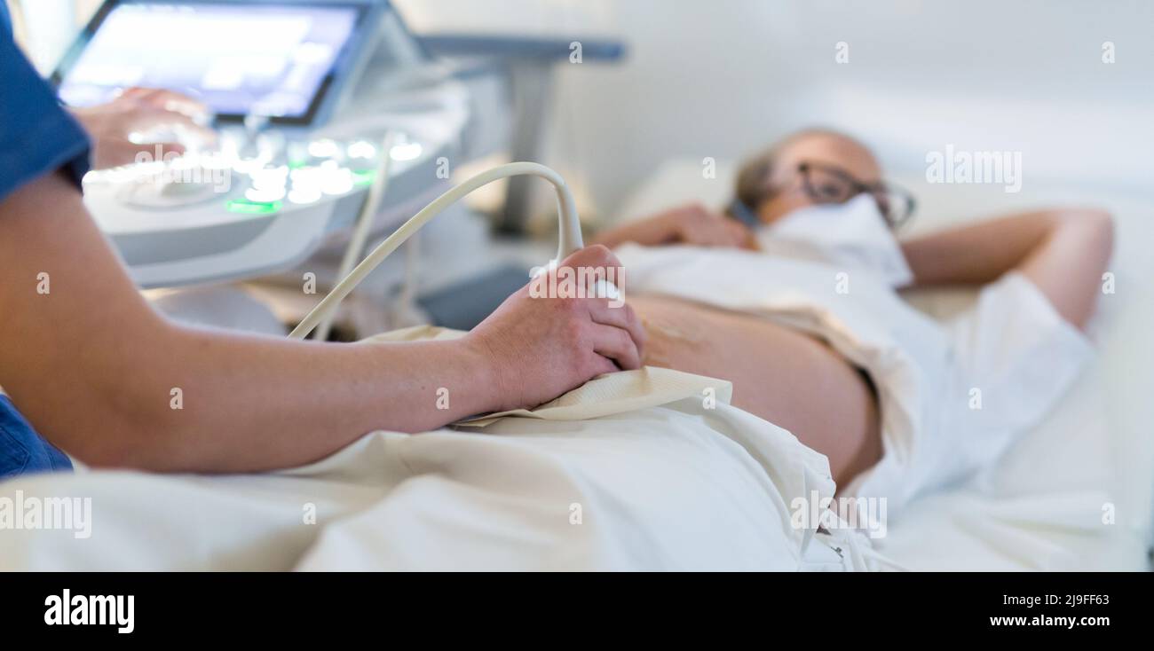 Primo piano di una donna incinta che esegue la scansione a ultrasuoni presso la clinica medica. Concetto di medicina e assistenza sanitaria Foto Stock