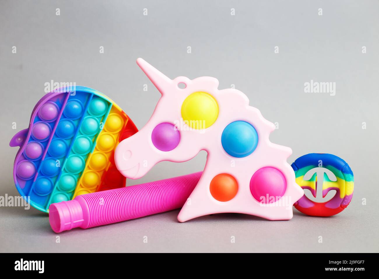 giocattoli colorati di fidget sensoriali antistress su sfondo grigio Foto Stock