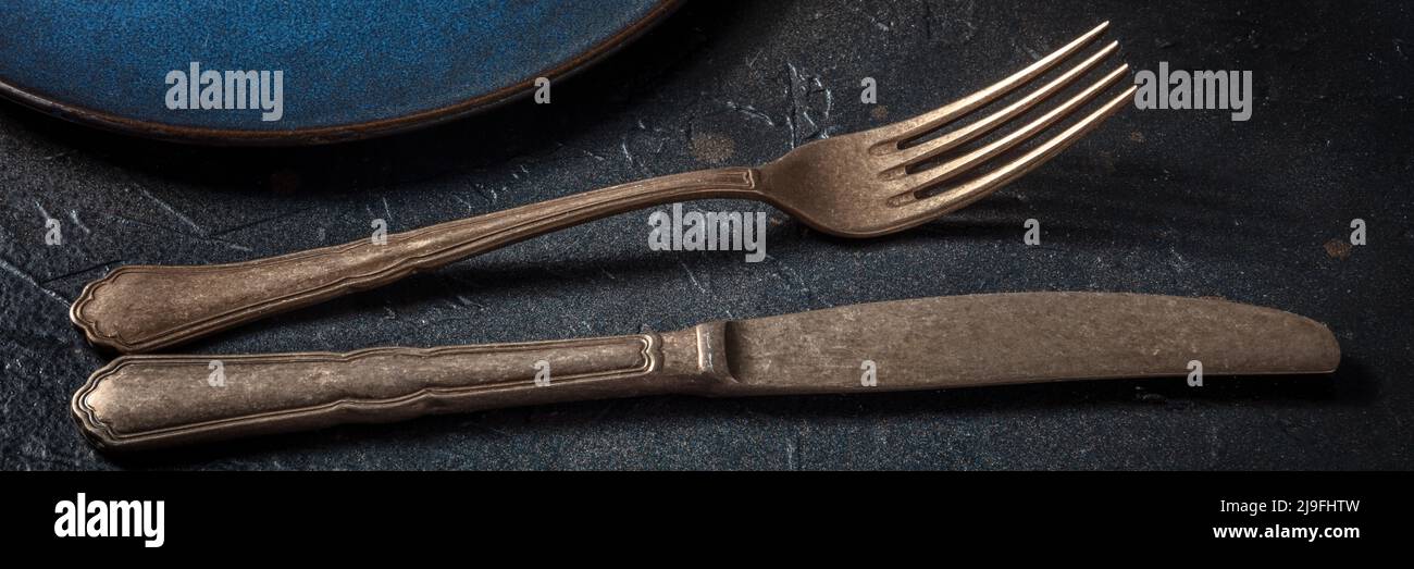 Posate su nero. Una forchetta e un coltello, argenteria su sfondo scuro, un panorama Foto Stock