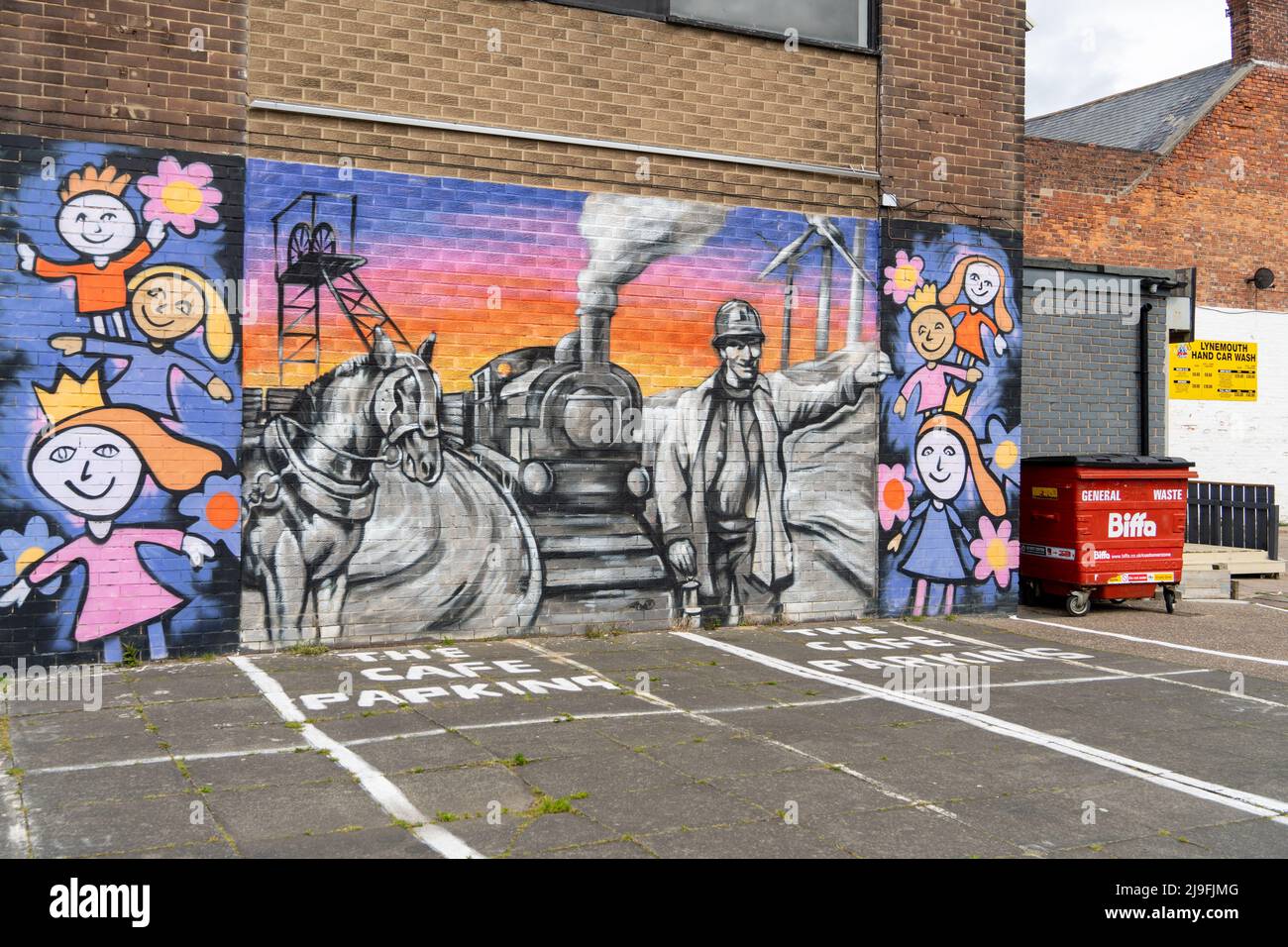 Un murale su un muro nella città di Lynemouth, Northumberland, Regno Unito, racconta la storia della sua industria e cultura - dall'estrazione del carbone alle fattorie eoliche. Foto Stock